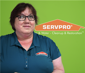 Woman smiling at the camera with a green background with a SERVPRO logo
