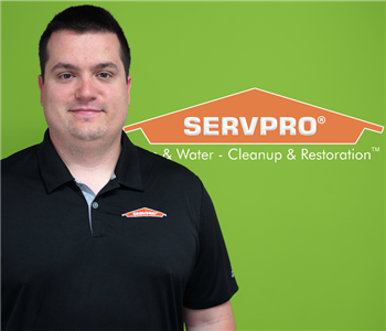 man smiling at the camera in a SERVPRO shirt on a green background